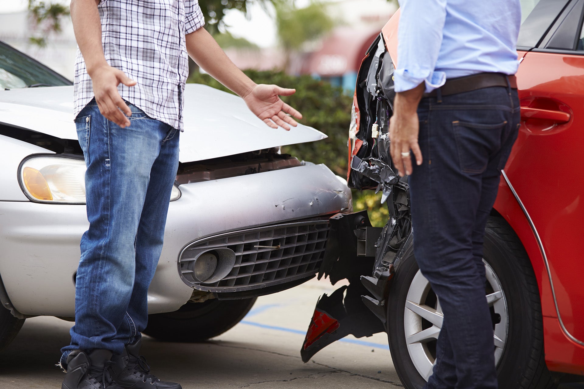 Two drivers inspecting vehicle damage after a car collision.